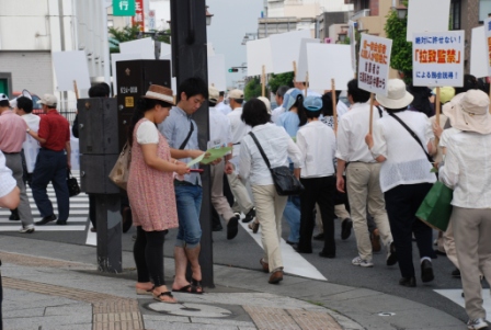 手渡されたビラに見入る通行人